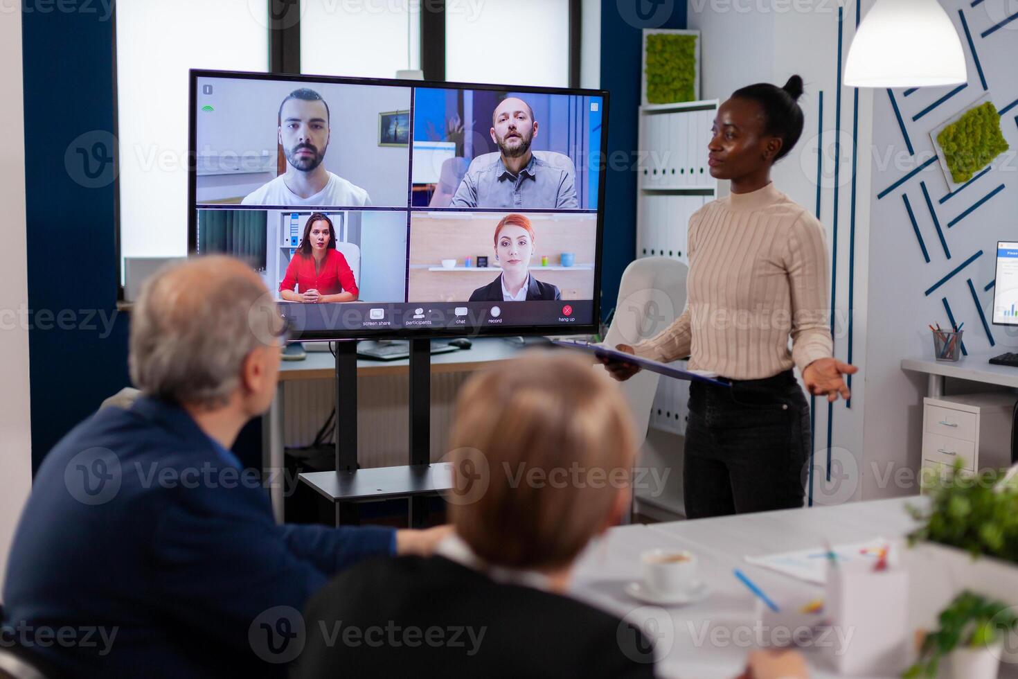 Black manager woman talking with remotely colleagues on call at tv screen, presenting new business partners. Business people talking to webcam, do online conference participate internet brainstorming, distance office discussion. photo