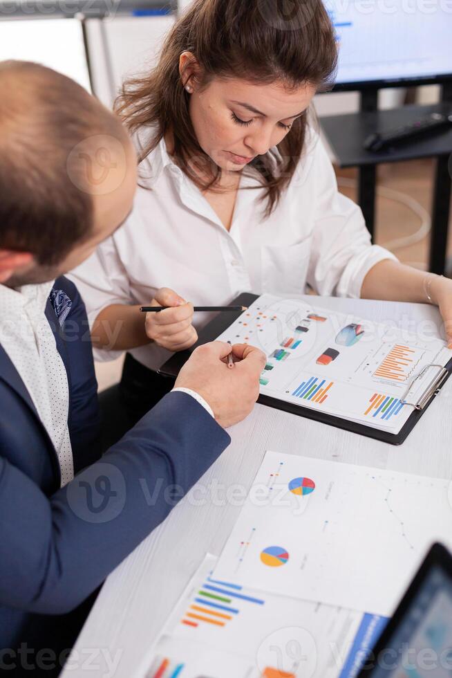 Colleagues of startup business discussing looking at documents in company board brainstorming conference room checking graphs and charts. Financial analysis during briefing. photo