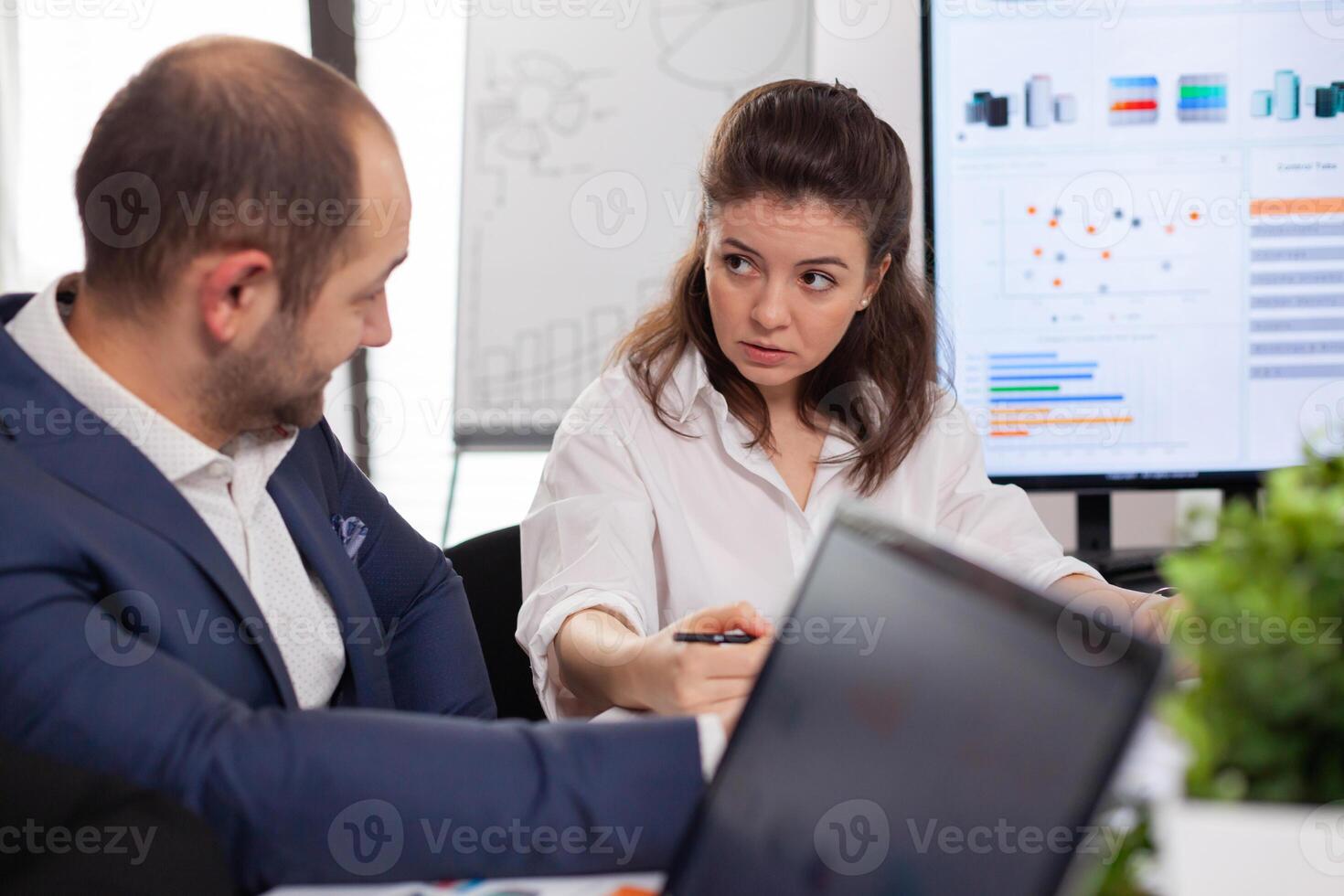 Colleagues of startup business discussing looking at documents in company board brainstorming conference room checking graphs and charts. Financial analysis during briefing. photo