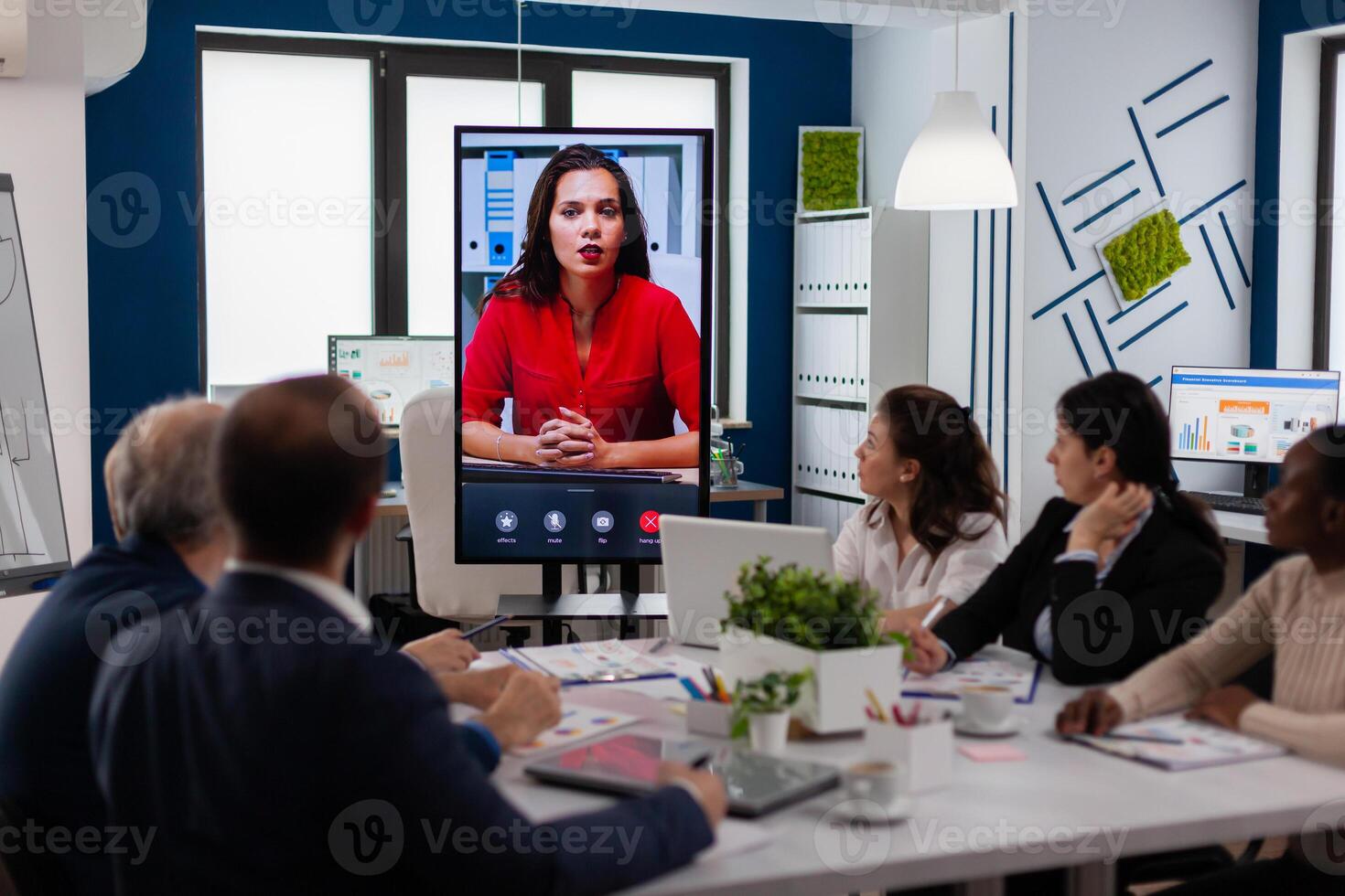 Diverse executive team meeting at conference call looking at huge display. Business people talking to webcam, do online conference participate internet brainstorming, distance office discussion photo
