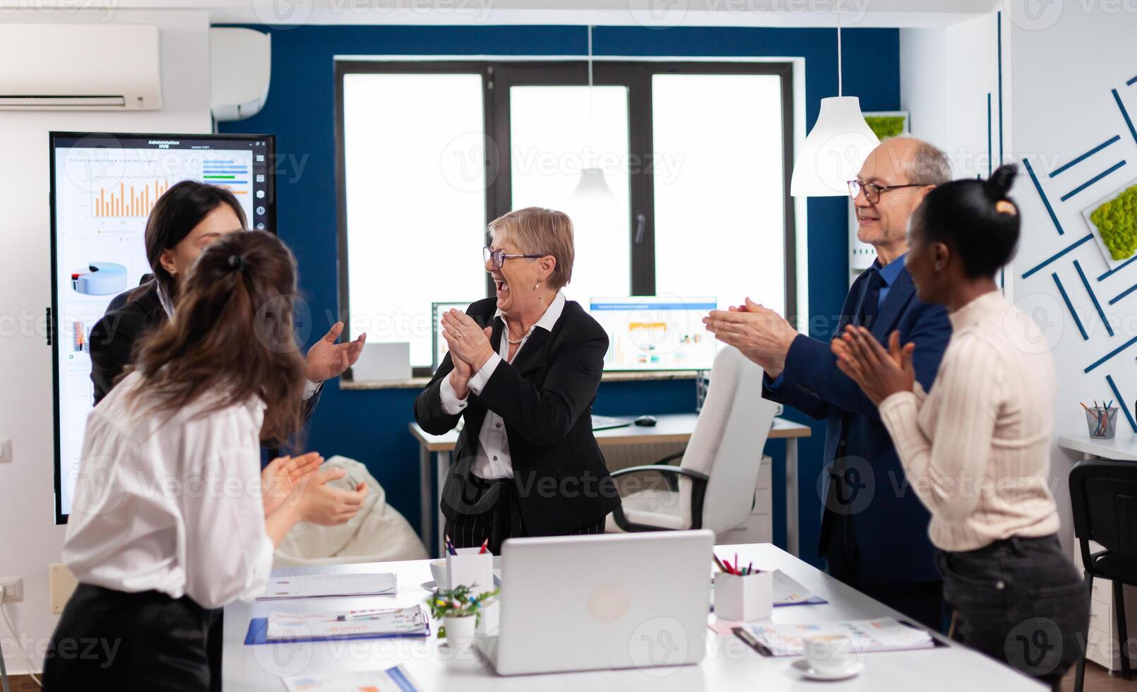 Happy excited diverse team of financial team in conference room after successful strategy. Multiethnical partners coworkers celebrate successful teamwork result at company briefing photo