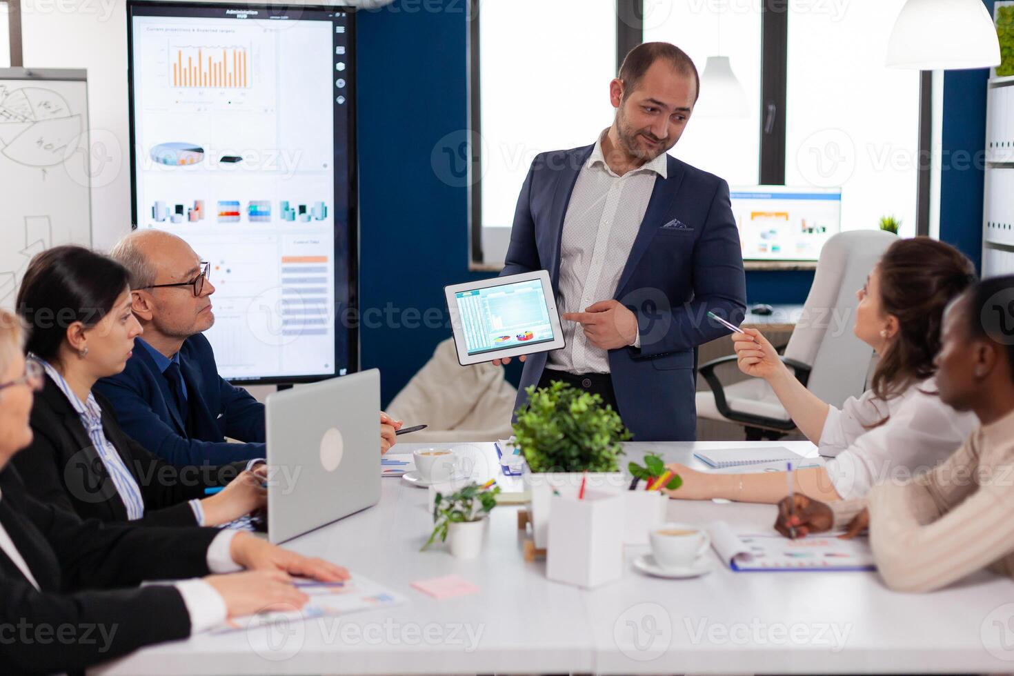 Company leadership explaining briefing project in conference room to team. Project leader discussing with teamworkers in broadroom, analysing charts, graphs, financial evolution of company. photo