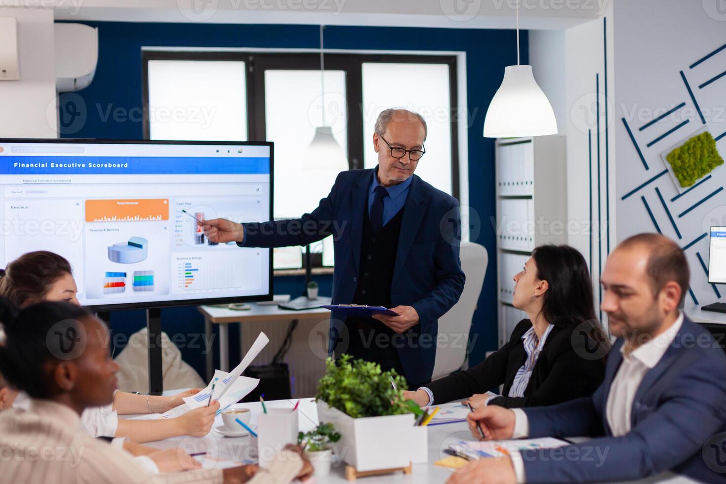 Senior manager holding business training explaining in conference room briefing. Corporate staff discussing new business application with colleagues looking at screen photo