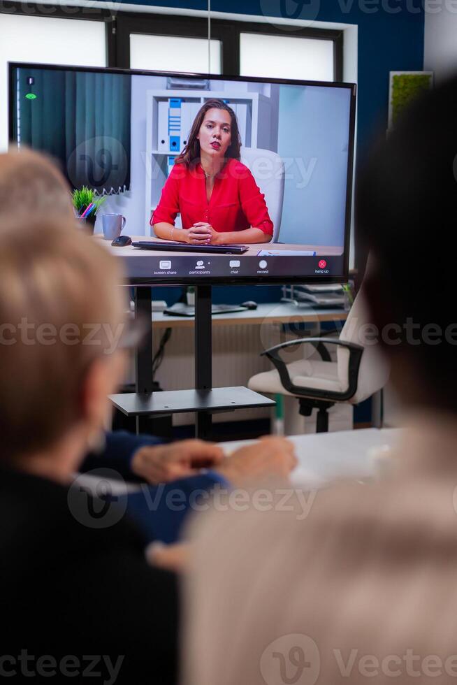 Diverse business team having videomeeting discussing online with remotely executive manager in business office. Business people talking to webcam, do online conference participate internet brainstorming, distance office discussion. photo