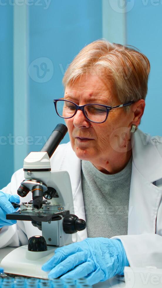 Woman research scientist looking at samples under microscope in modern equipped laboratory in the night. Working with various bacteria, tissue and blood tests, pharmaceutical research for antibiotics photo