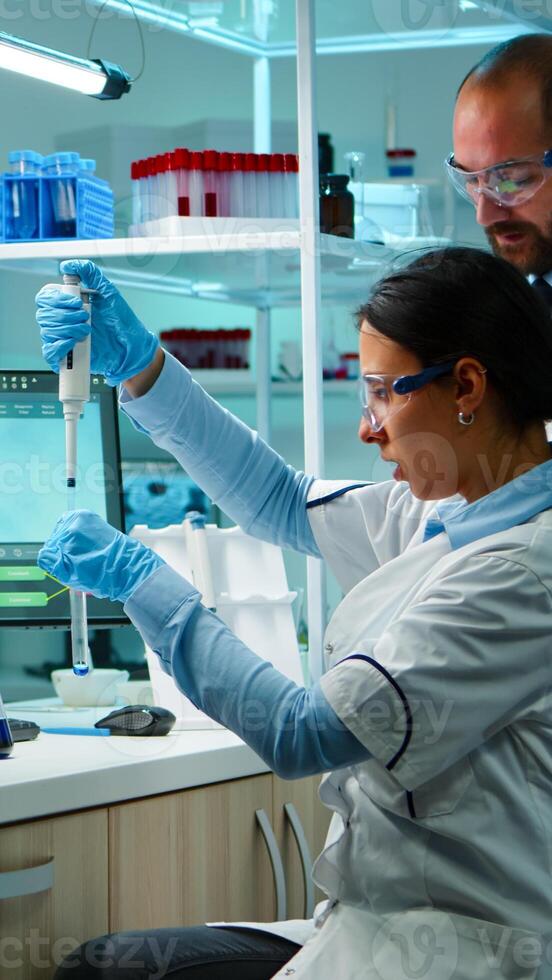 Scientist woman pipetting liquid to test tube working in equipped lab late at night. Chemists examining virus evolution using high tech for scientific analysis of treatment development against covid19 photo