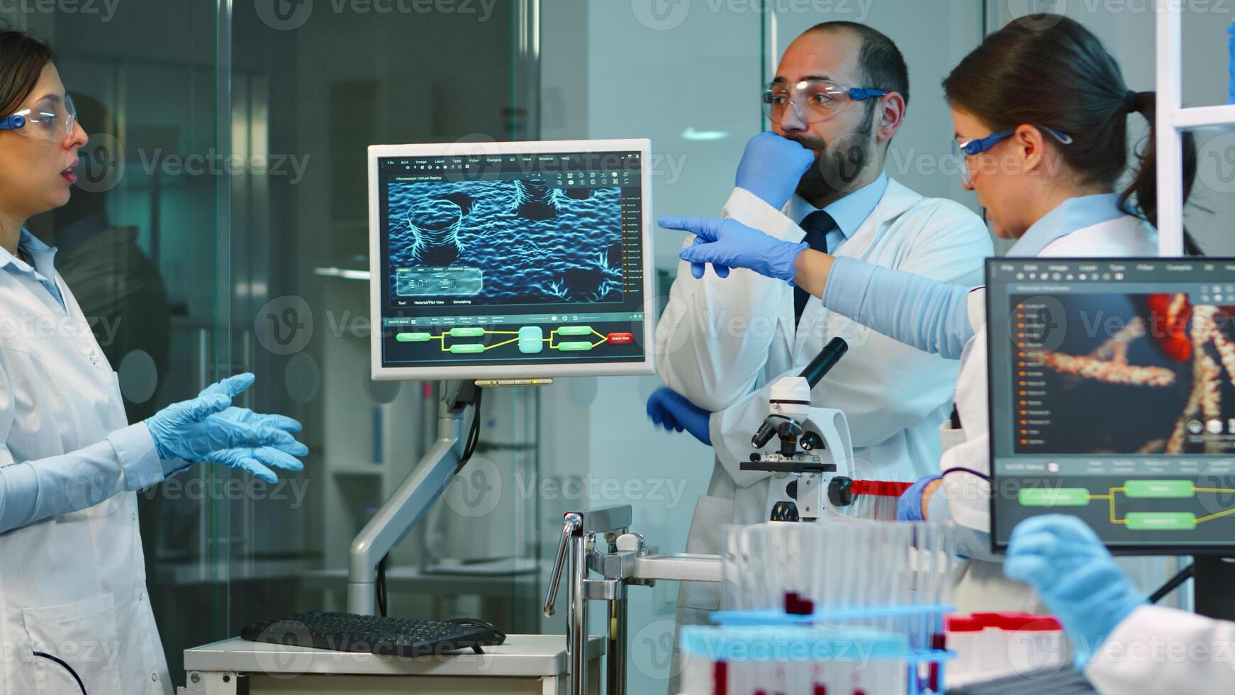 Team of medical researchers conducting vaccine development with help of high tech, test tubes, micropipette analysing results and planning next steps working at night in modern equipped laboratory photo