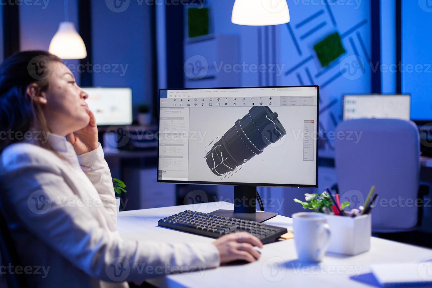 Project designer engineer analizing concept idea of 3D model of the plant yawning working overtime. Industrial woman worker studying turbine idea on pc showing cad software on device display photo