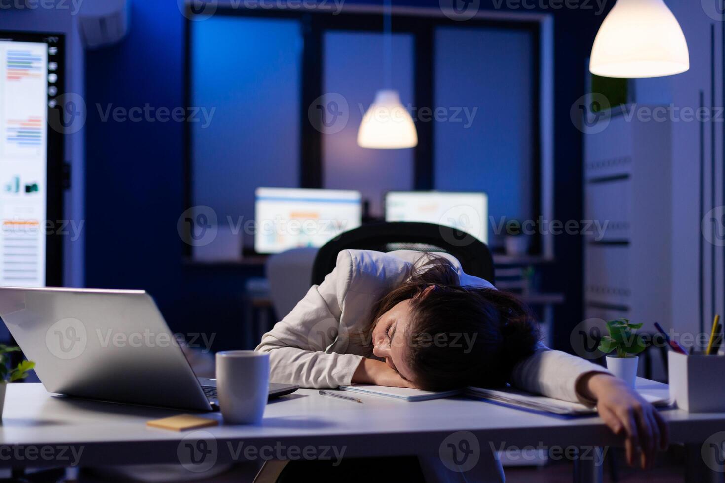 Exhausted overload business woman falling asleep on desk with open laptop while working on marketing project in start up company office. Entrepreneur using modern technology network late at night photo