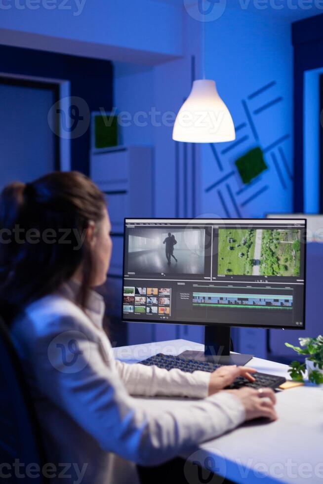 Creative content creator working at postproduction montage to respect deadline sitting at desk in start-up business office. Woman videographer editing audio film on professional laptop at midnight. photo