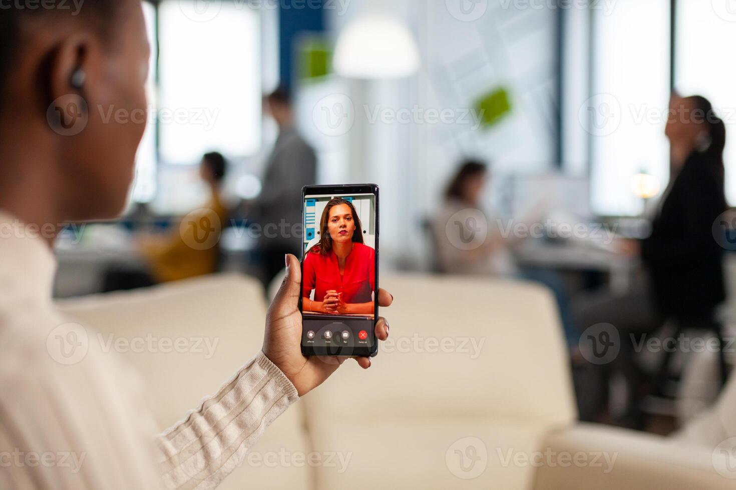 Over the sholder of black employee discussing with partner on call using phone in start up business office. Black woman during meeting, online conferencel planning new financial project photo