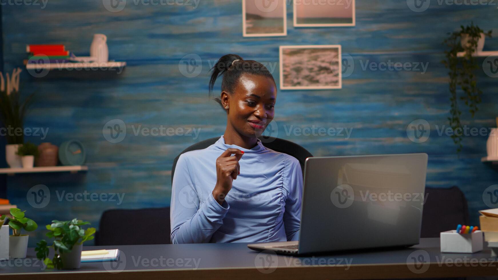Smiling african american freelancer listening music working on laptop dancing sitting at desk in living room workplace. Black woman enjoy e-learning process, easy application usage overtime. photo