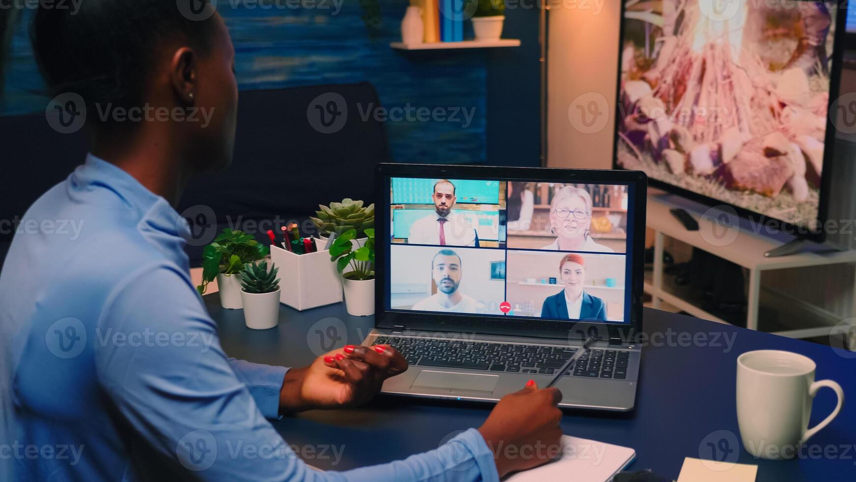 Remote black employee having conference working from home sitting in living room late night. Freelancer using technology network wireless talking on virtual meeting at midnight doing overtime photo