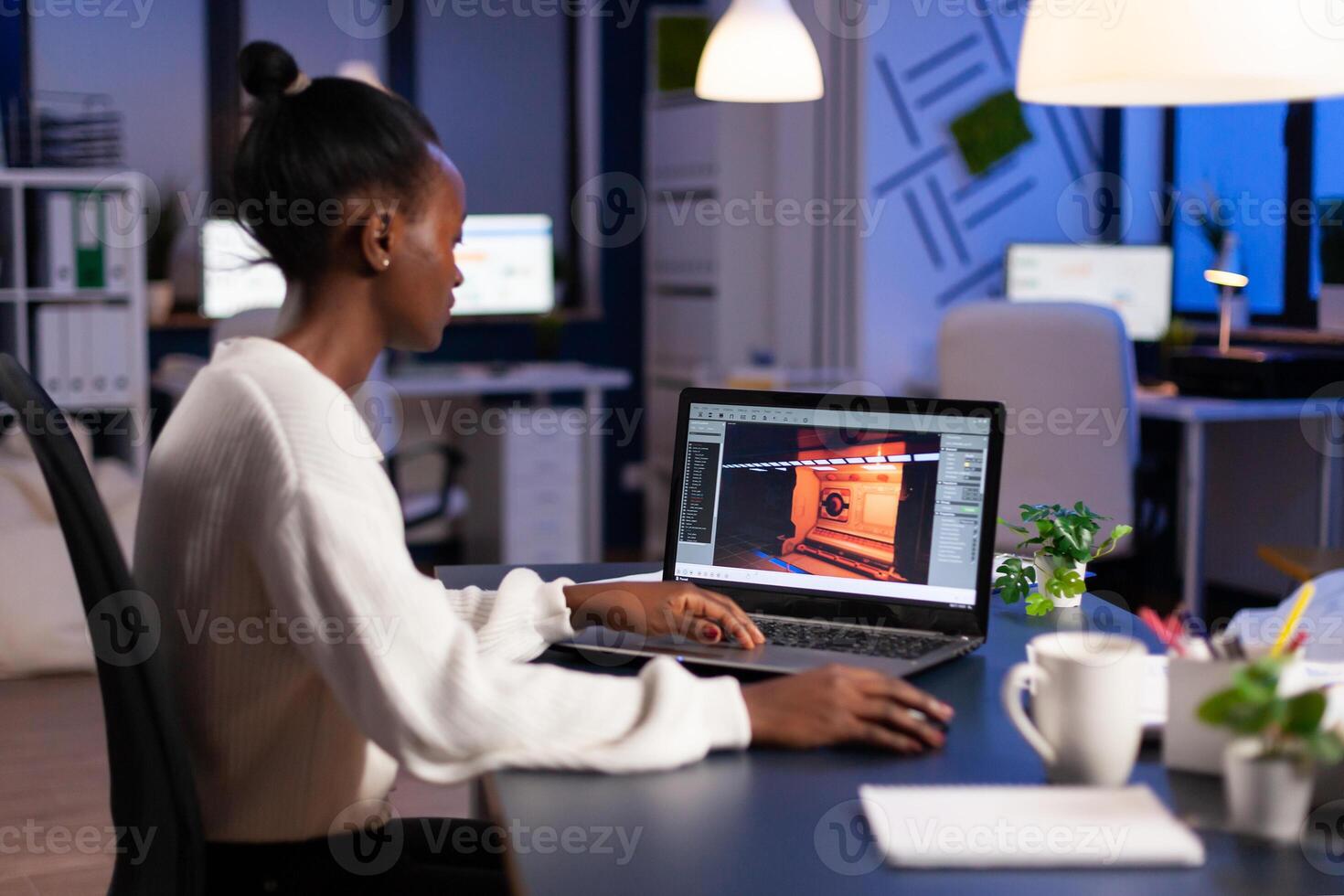 Dark skin gamer developer working at game in midnight from business office using professional laptop. African player testing online games on pc with modern technology network wireless. photo
