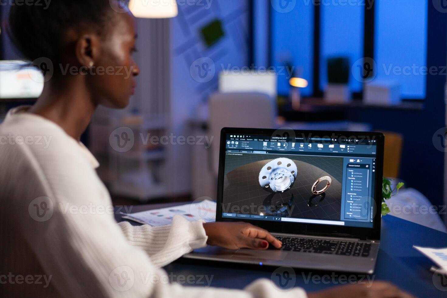 African american engineer developing engineering gear design working at industrial mechanical prototype late at night in startup company office. Project designer using industry construction software photo