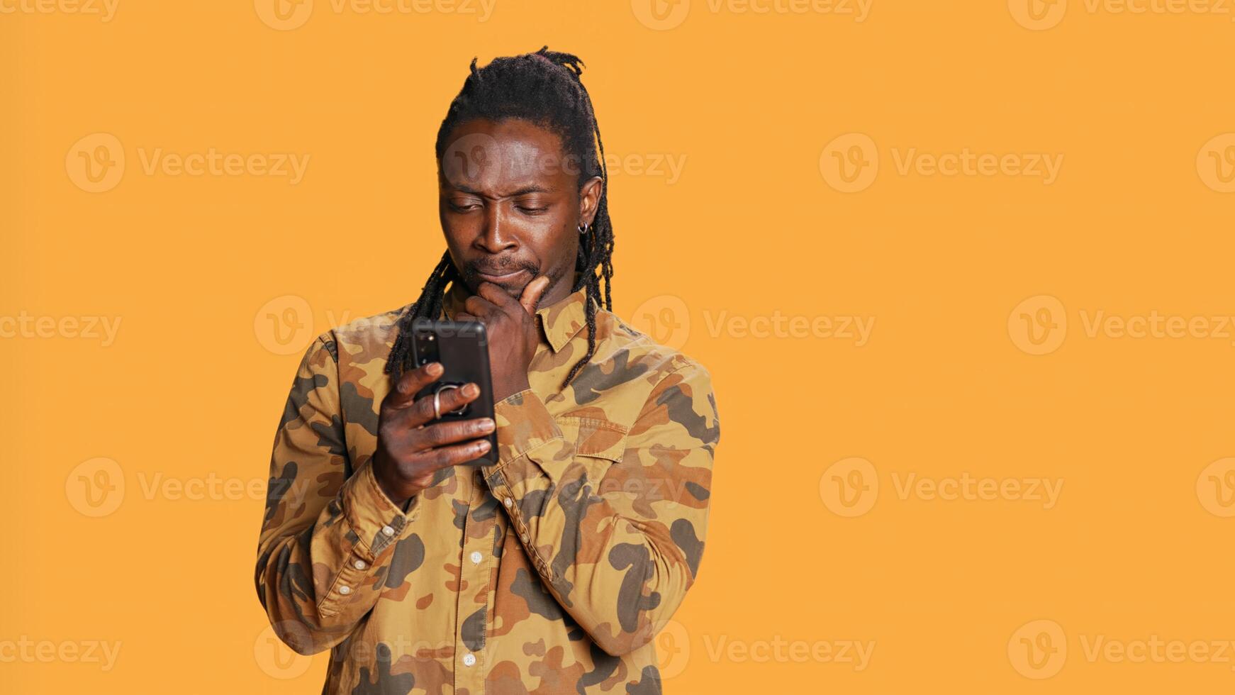 Modern guy navigating online websites on smartphone, checking his chats for texts and posing on camera. African american person using mobile apps to stay connected with friends. Handheld shot. photo