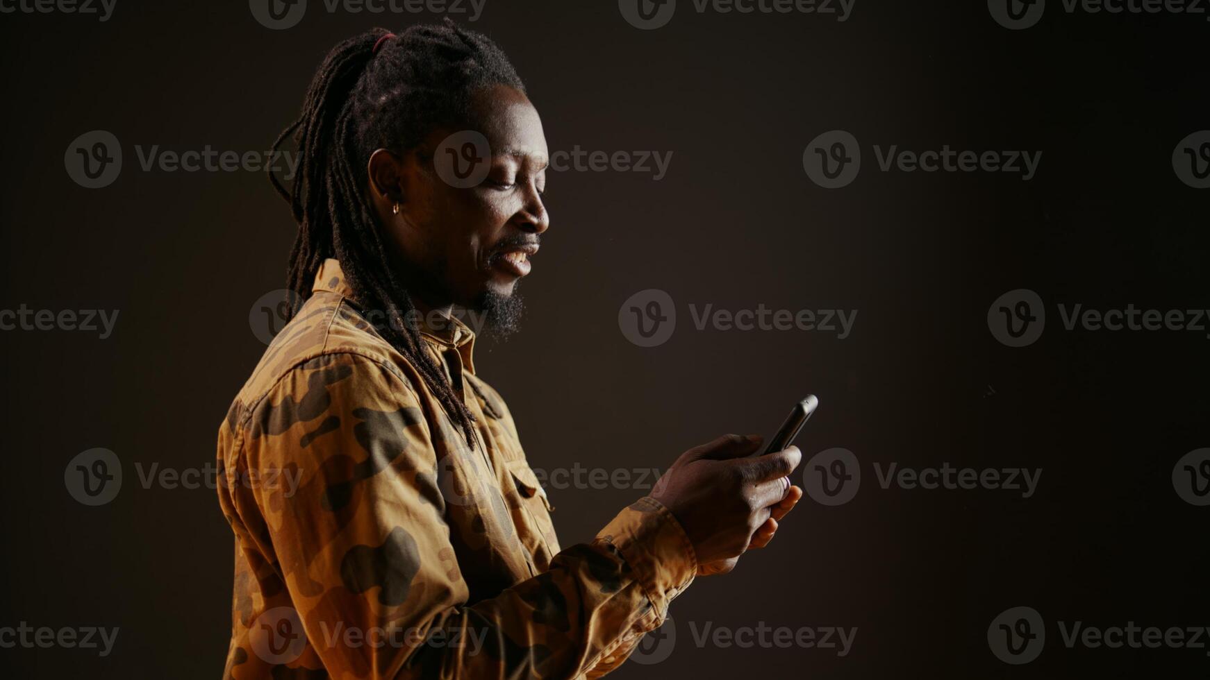 Modern person browsing online webpages on mobile phone, checking his socials for texts and posing in studio. African american man using smartphone apps to stay connected with friends. photo
