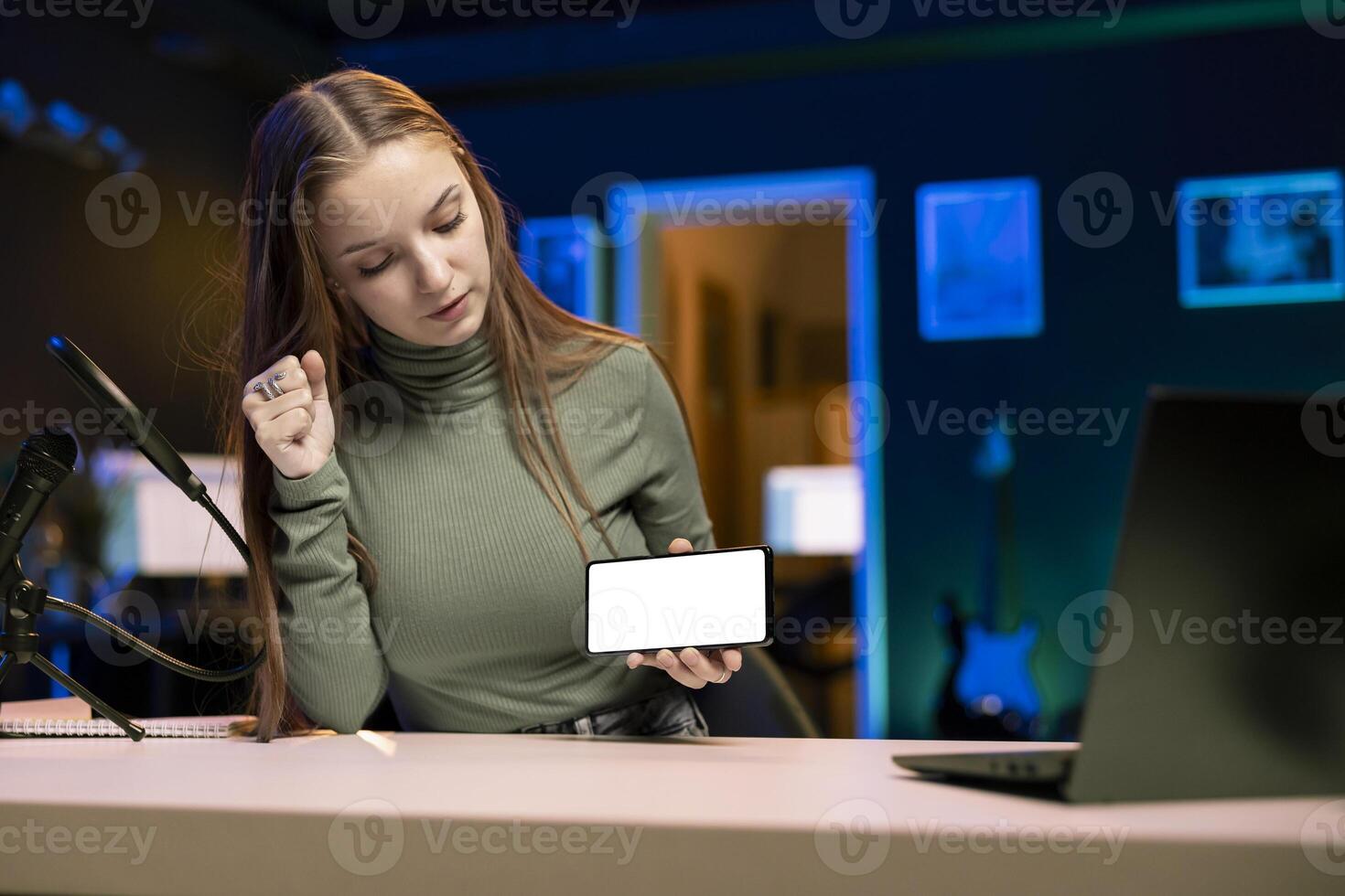 Young content creator filming technology review of newly released isolated screen smartphone, unpacking it and presenting specifications to audience. Internet star showing mockup mobile phone to fans photo