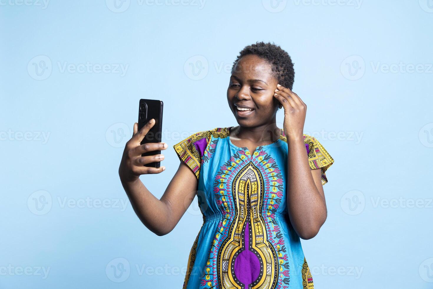 African american model attending online videoconference call, waving at her friends on videocall in studio. Cheerful woman feeling happy while she is having a remote discussion on web network. photo