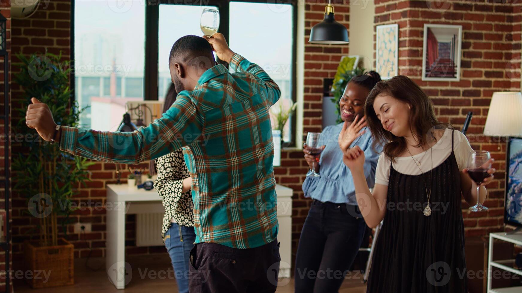 Young adults of various nationalities dancing at home party while drinking alcohol. Friends hanging around, having good time together while enjoying upbeat music in living room photo