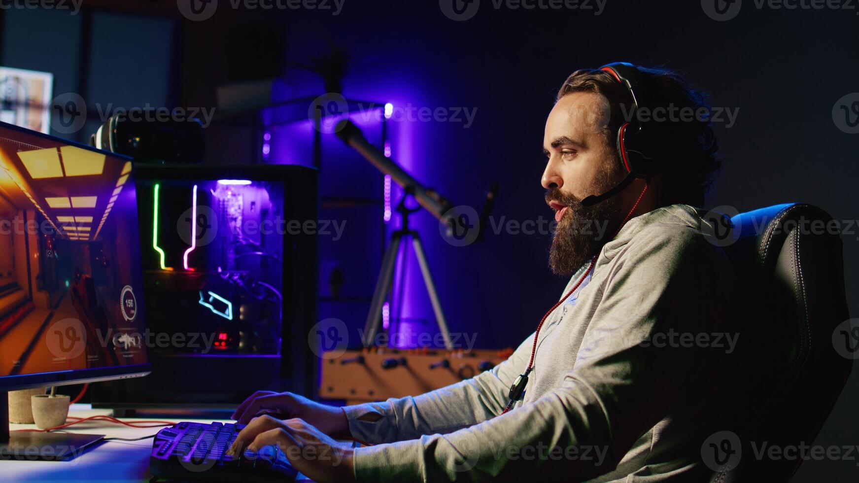 Man playing science fiction FPS videogame with friends, having fun in dark apartment room. Gamer competing in PvP online multiplayer game, talking with internet players through headphones mic photo