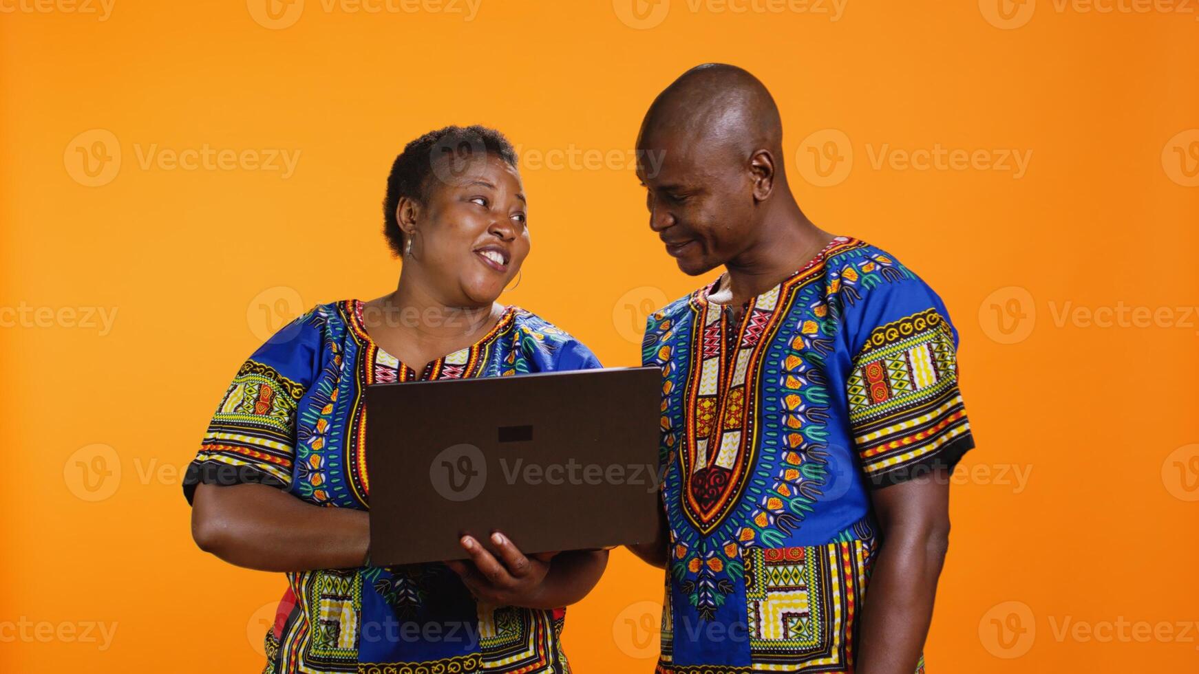 Husband and wife searching information on online website, holding laptop in front of camera for social media browsing. African american ethnic people using pc to check web browsers. photo