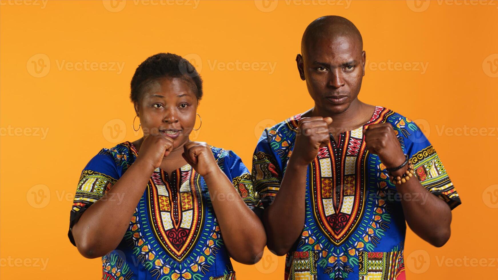 Aggressive strong people clenching fists on camera and preparing for boxing fight. Furious violent ethnic couple acting dangerous and being ready to beat someone, battle conflict. photo