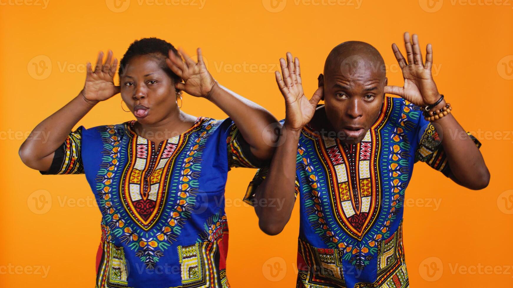 African american silly couple fooling around on camera, sticking tongue out and having fun with jokes in studio. Ethnic man and woman laughing together and acting playful. photo