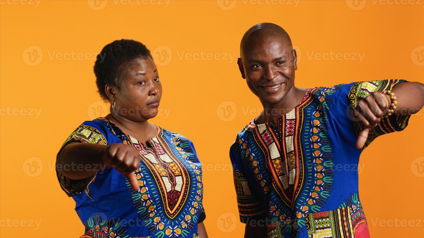African american couple showing thumbs down sign, giving dislike symbol in front of camera and expressing disagreement. Negative man and woman presenting disapproval and bad review. photo