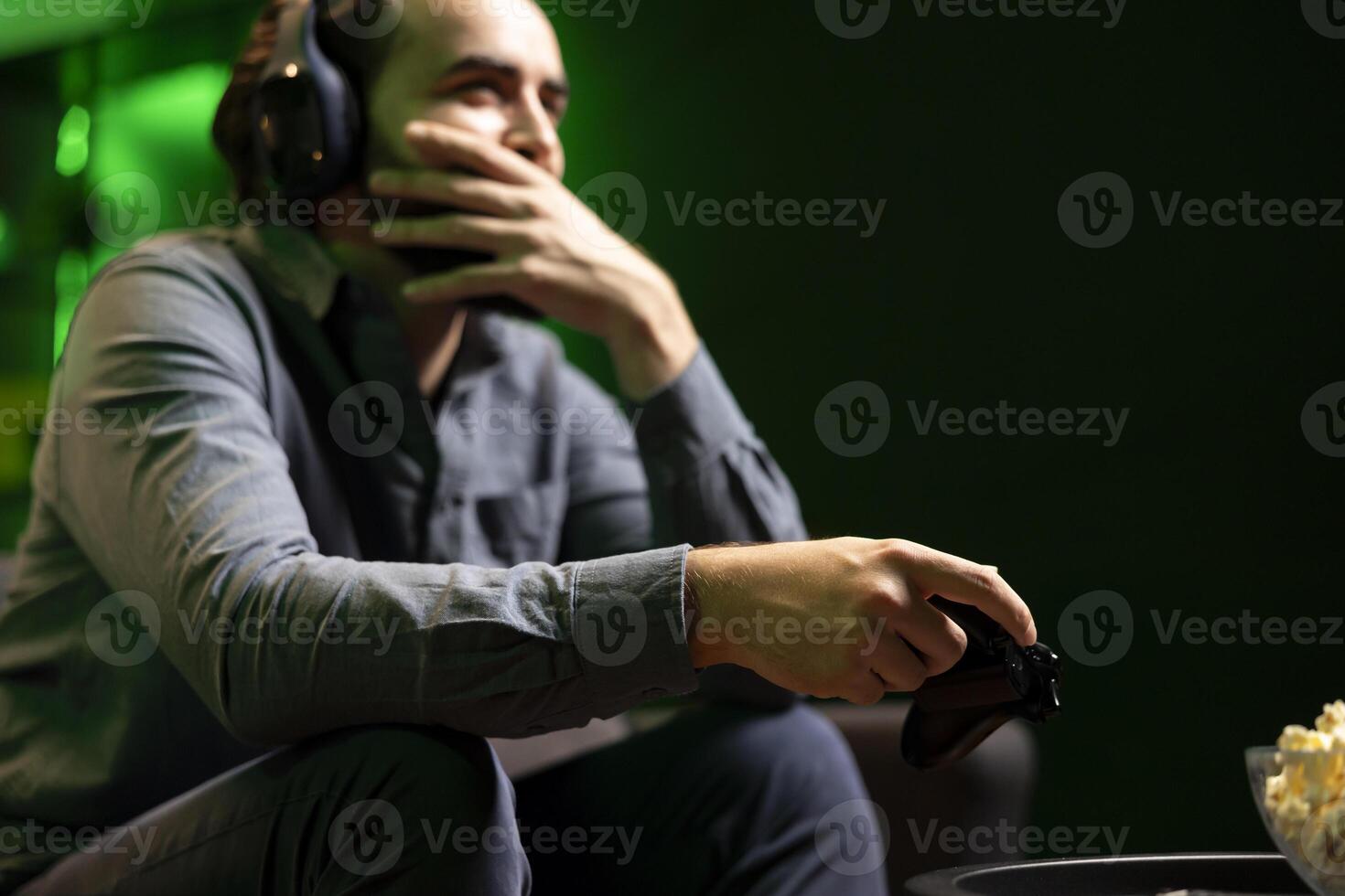 Man having fun and laughing while playing games on gaming console, talking with teammates using headphones mic. Happy gamer battling rival players using controller, amused by friends during chat photo