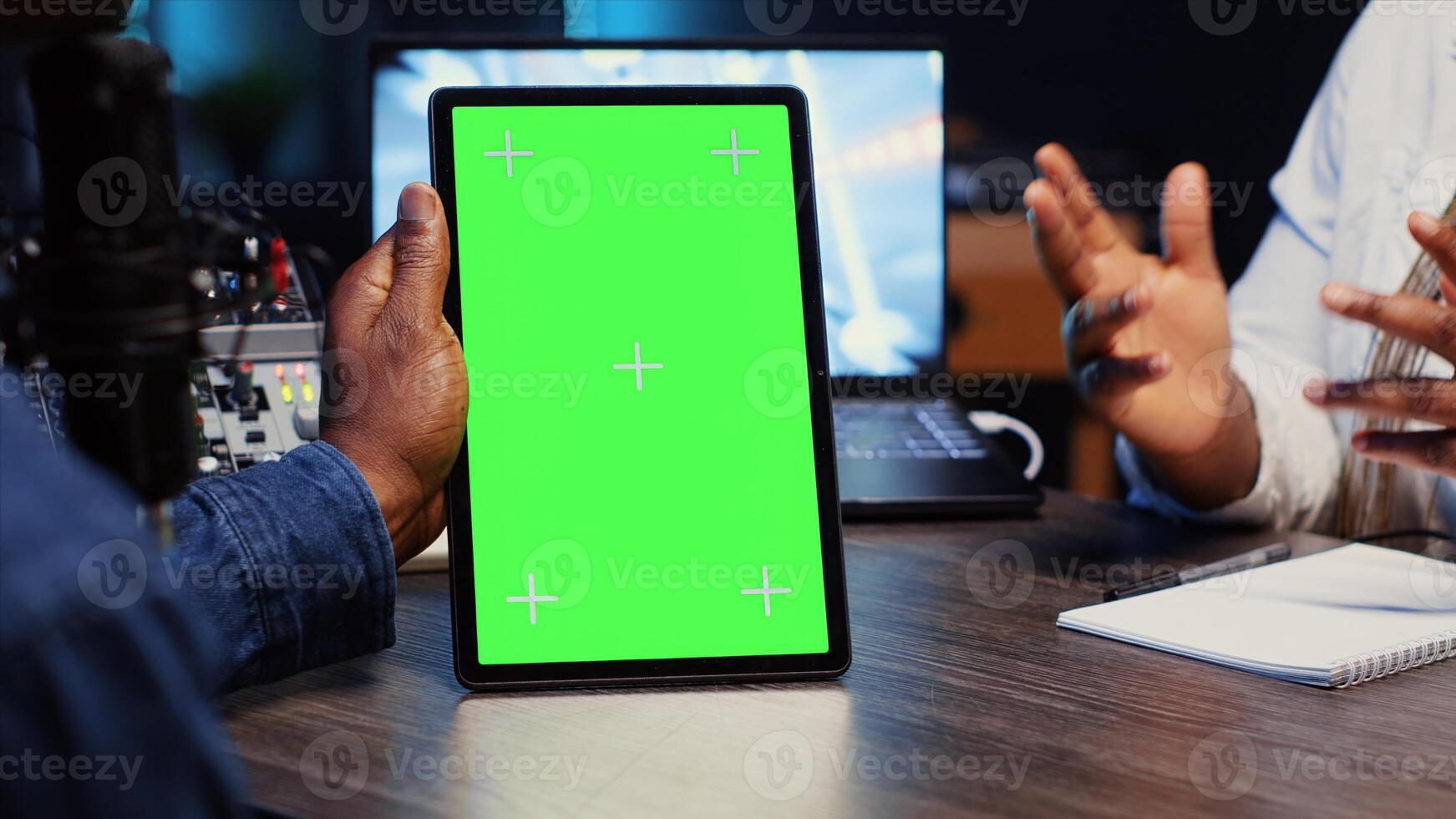 Green screen tablet held by vlogger show host chatting with guest in neon lights ornate living room studio. Close up shot of mockup device used by man and woman broadcasting discussion on podcast photo