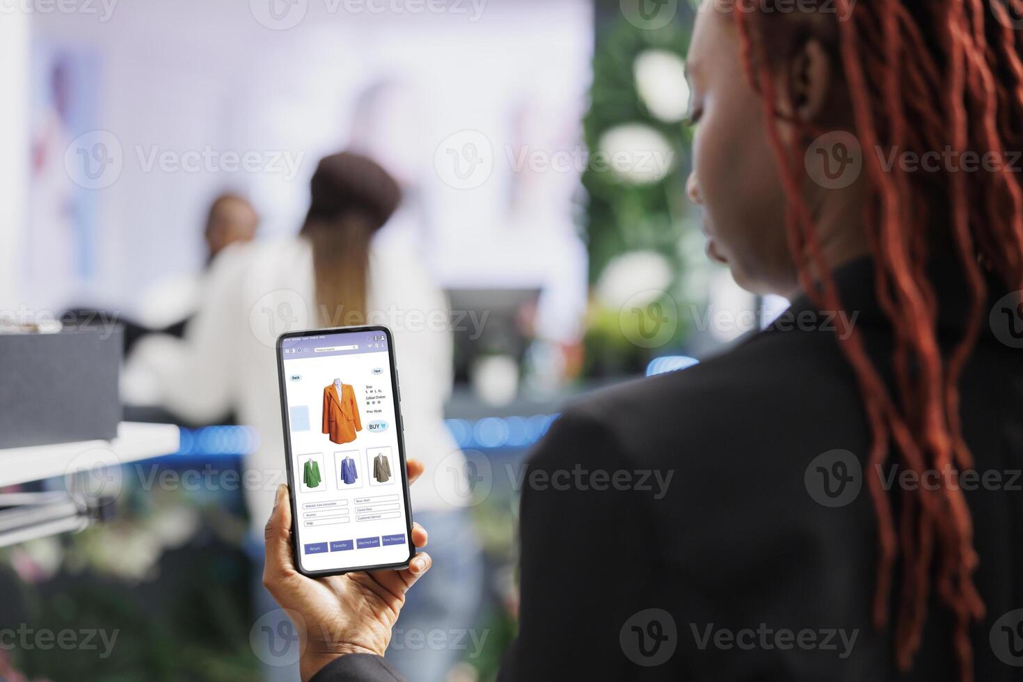 Customer looking at online clothing app shop, buying clothes on website while she sits in fashion boutique at mall. Buyer shopping online on digital store, retail merchandise items. photo