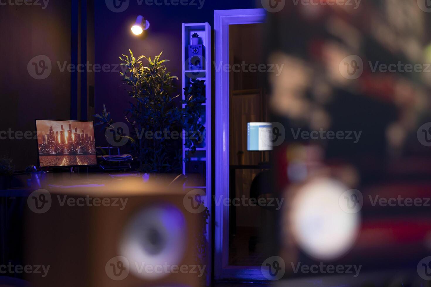 3D animation left open on PC screen in background in empty neon illuminated apartment living room. 3D rendering on computer desktop display in RGB lit home late at night with no people in photo