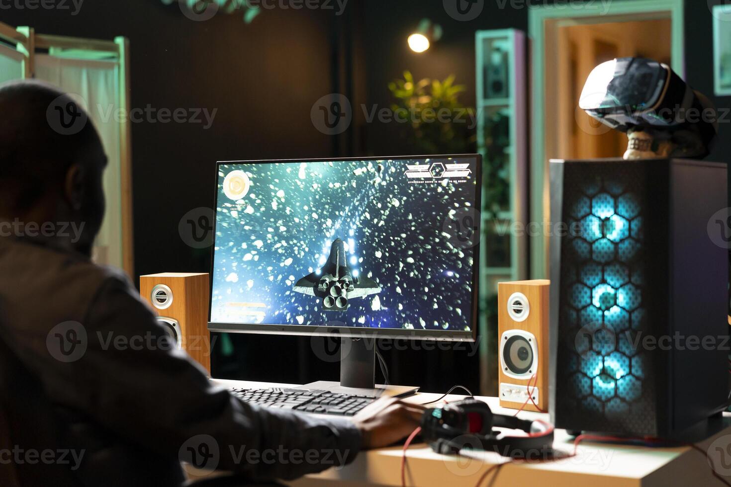 African american player at home shooting asteroids in spaceship flying singleplayer game with overlay HUD showing health levels on monitor. BIPOC person navigating universe in simulation game on PC photo