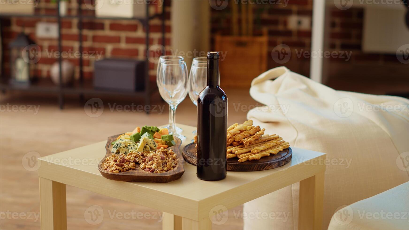 Panning shot of appetizers board and gourmet cheese platter set up by hosts to properly welcome guests arriving soon at social gathering. Wine bottle and glasses next to food in cozy home, close up photo