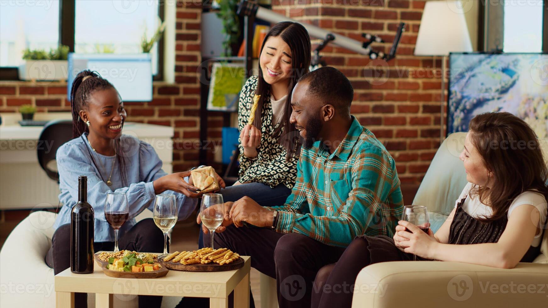 Multiracial friends throwing surprise birthday party forafrican american man, giving him thoughtful gift in living room. Smiling group of people celebrating host anniversary, gifting nice present photo