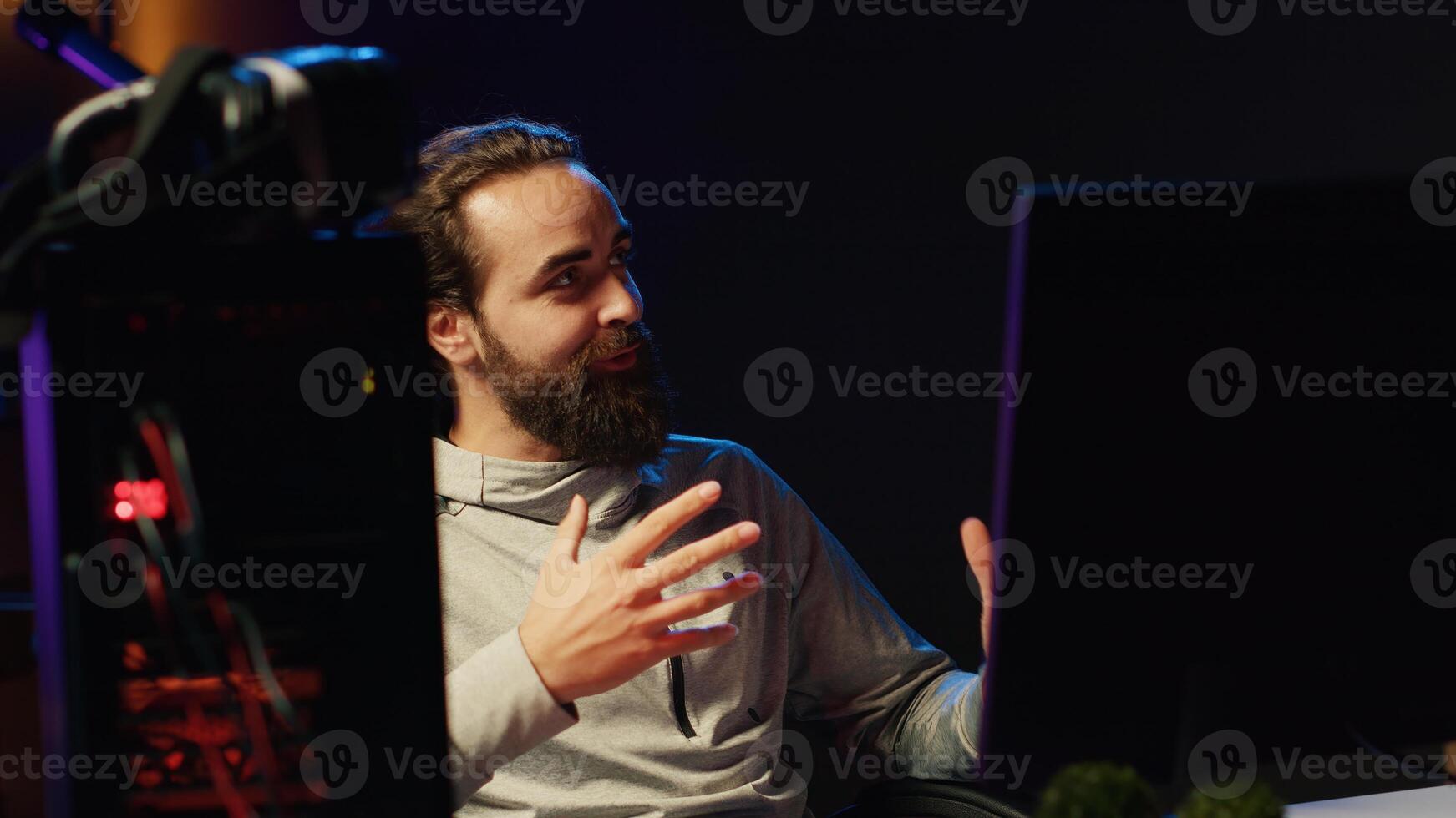 Streamer talking to viewers live, presenting next game he will play, providing info and reviewing. Pro gamer broadcasting from dark apartment, greeting fans watching him on online channel photo