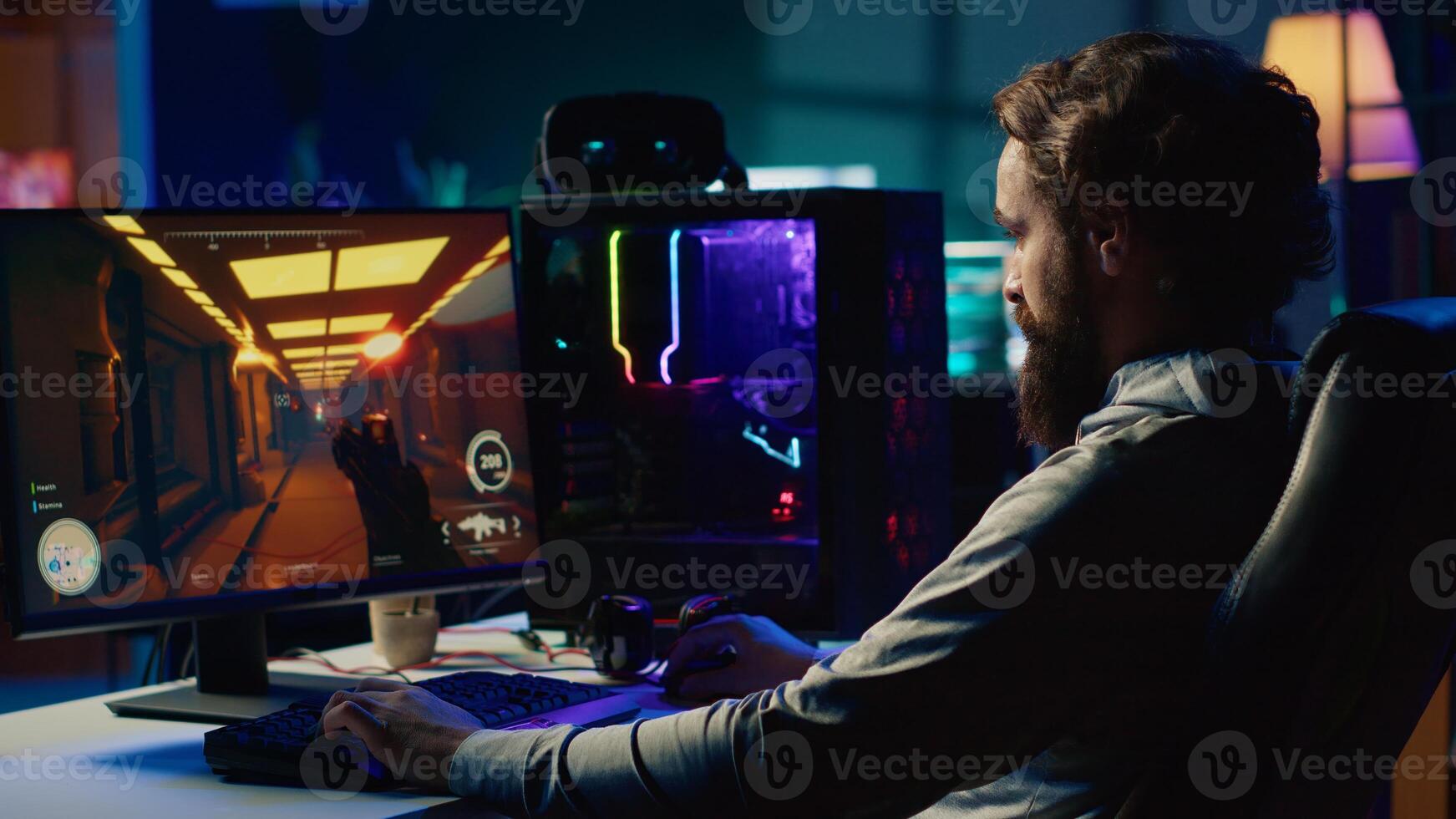 Portrait of smiling man in dimly lit apartment playing games on gaming PC at computer desk, enjoying day off from work. Gamer battling enemies in online multiplayer shooter photo