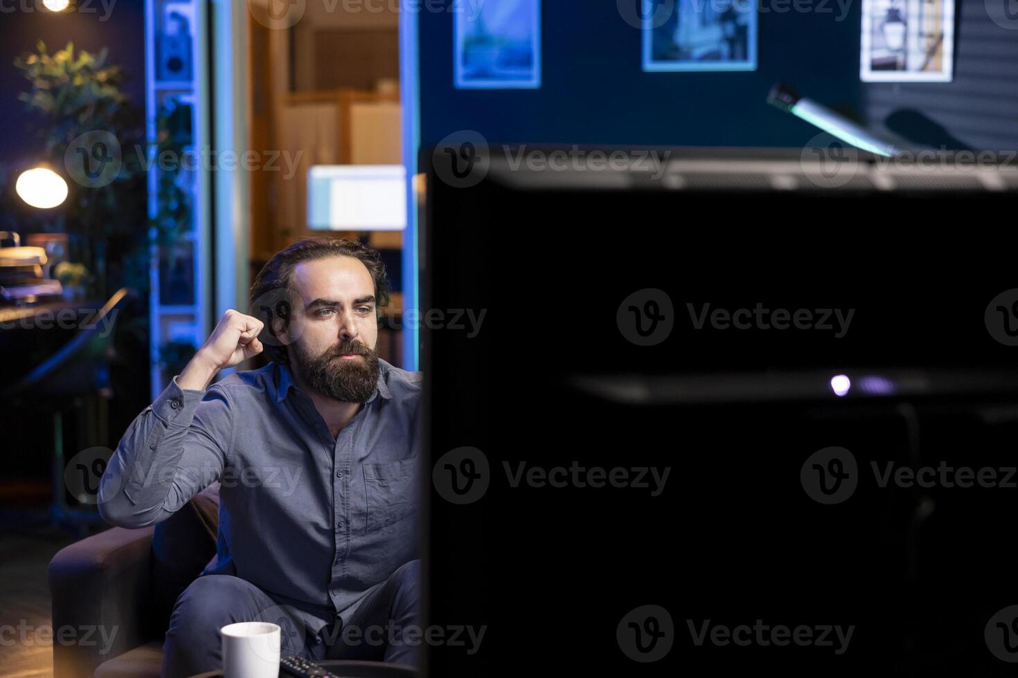 Fan satisfied by seeing favorite team win while watching live sports event broadcasted on TV, clutching hands. Supporter pleased with own club achievement after getting victory in football competition photo