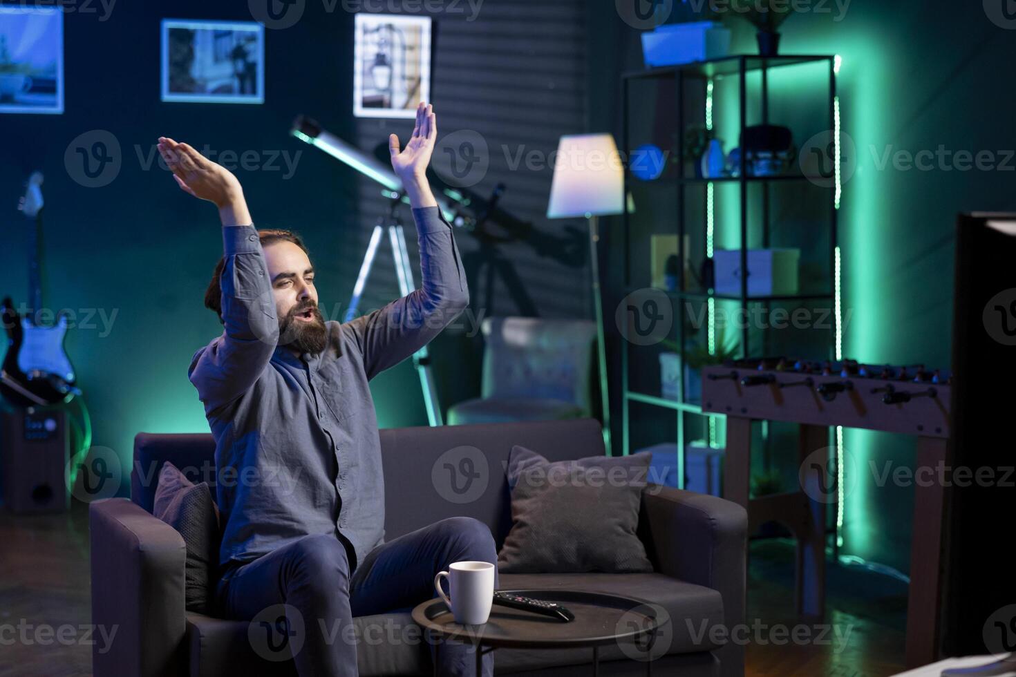 Jolly man clapping hands after favorite team wins while watching live sports event broadcasted on TV. Happy supporter applauding own club, enjoying football competition victory photo