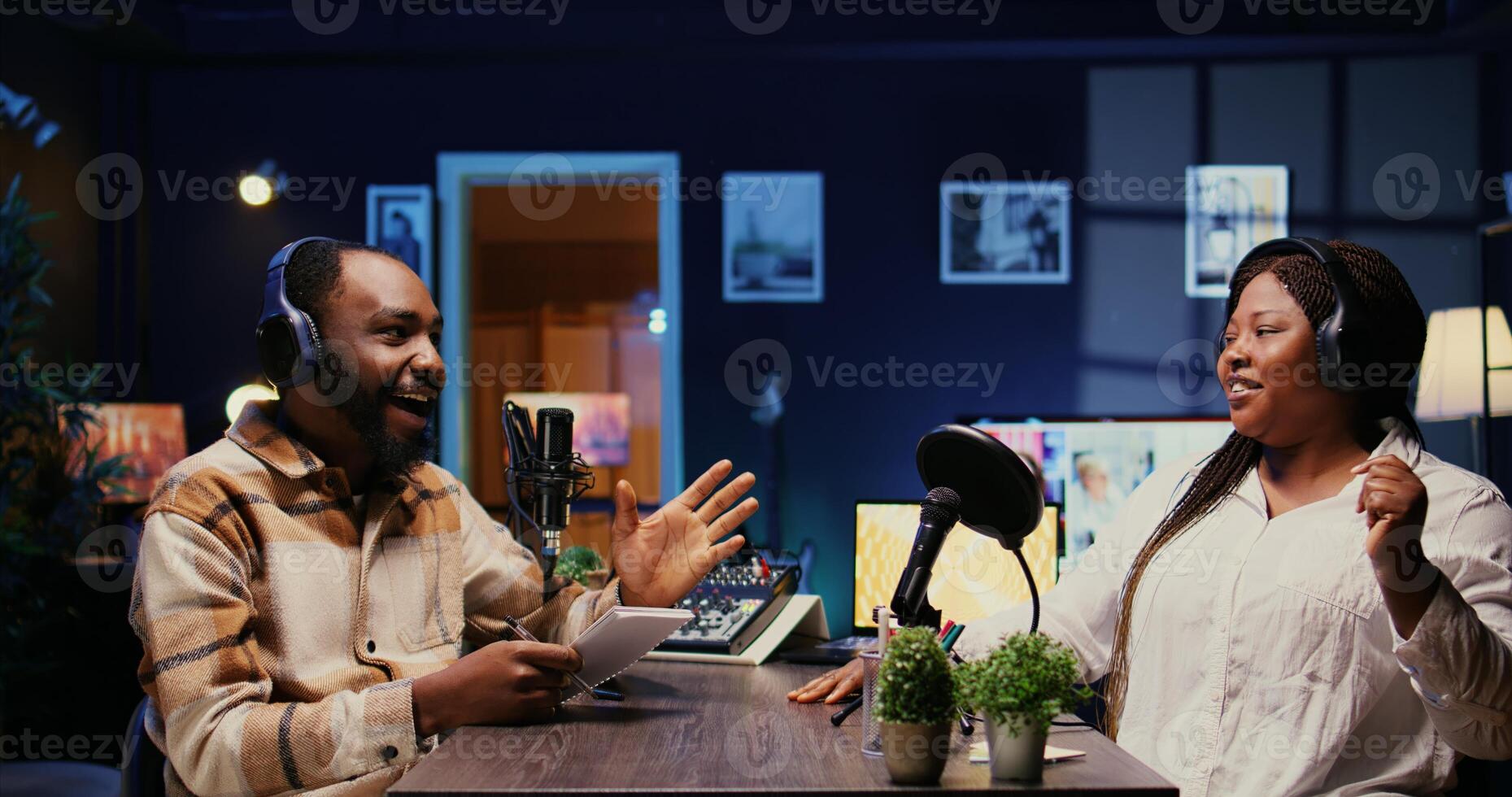 Vlogger show host interviewing guest in neon lights ornate studio, following questions written on paper. Man filming online podcast episode with woman, discussing about personal life photo