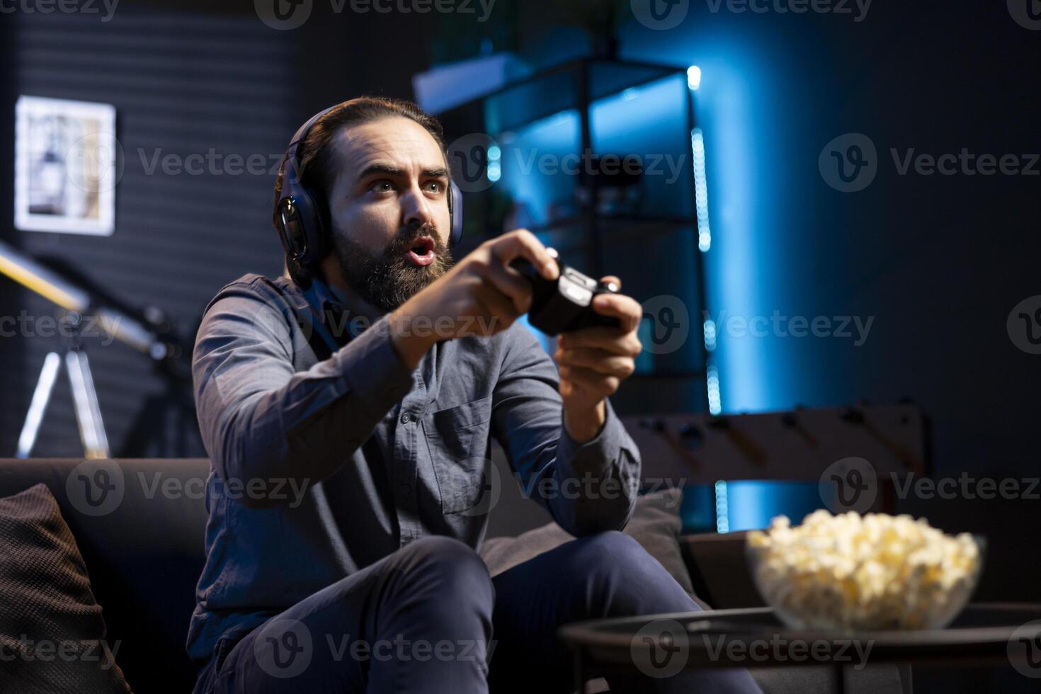 Man showing surprise facial expression while playing videogames on gaming console with teammates. Player acting shocked after being defeated by foes in game, discussing with friends through headset photo