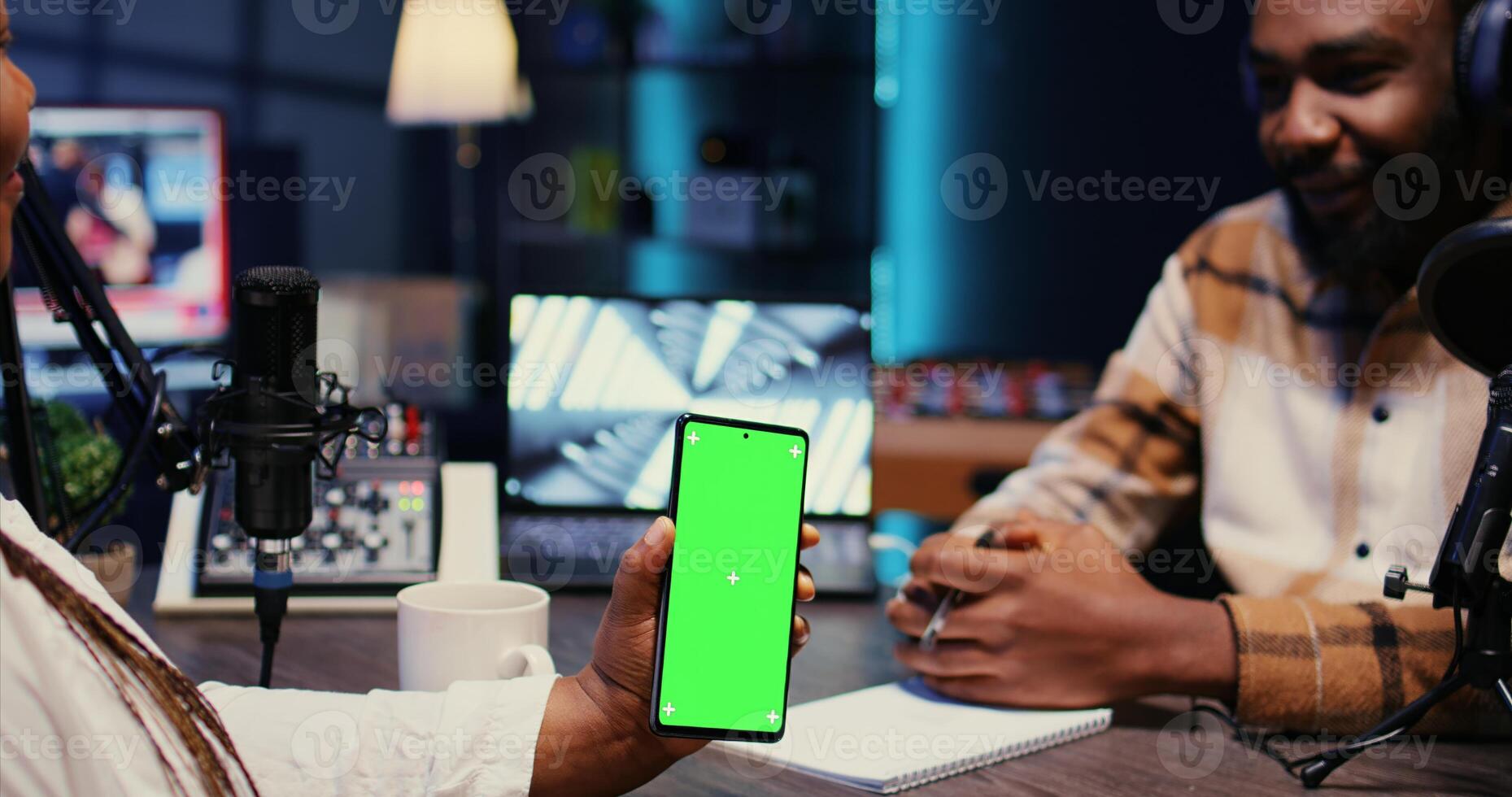 Isolated screen cellphone in front of show presenter recording podcast, enjoying cup of coffee and nice conversation with guest. Chroma key phone in studio used for live broadcast with woman photo