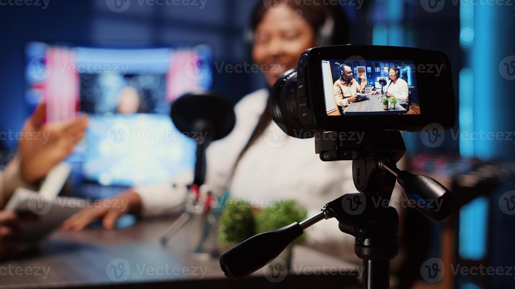 Focus on professional camera recording man in blurry background using high tech microphones to interview guest, ensuring optimum and sound quality for audience watching at home, close up photo