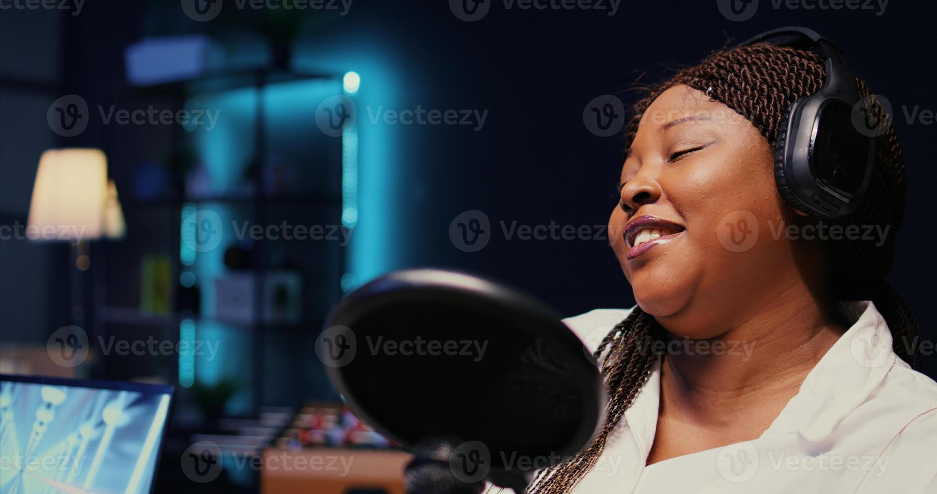 Zoom in on african american woman streaming podcast using vlogging camera during live political debate on vlog channel. Internet show presenter in dimly lit studio, close up photo