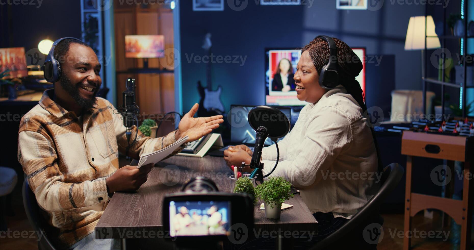Cohosts streaming podcast using vlogging camera during live debate on vlog channel, handheld camera shot. Man and woman meeting in studio to film show with professional equipment photo