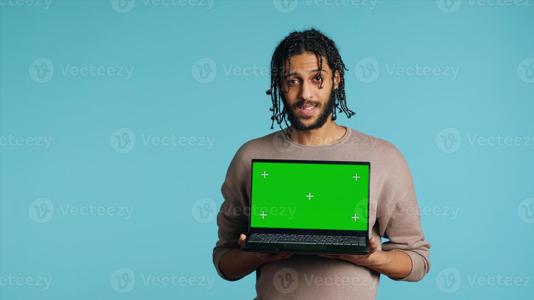 Joyous BIPOC man holding green screen laptop, having positive mood. Smiling person presenting chroma key notebook, doing recommendation, isolated over studio background, camera A photo