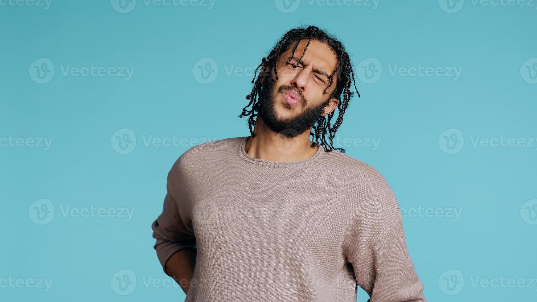 Hurt Middle Eastern man screaming from pain, suffering from back injury, having health problems. Injured BIPOC person feeling uncomfortable ache, yelling, studio background, camera B photo