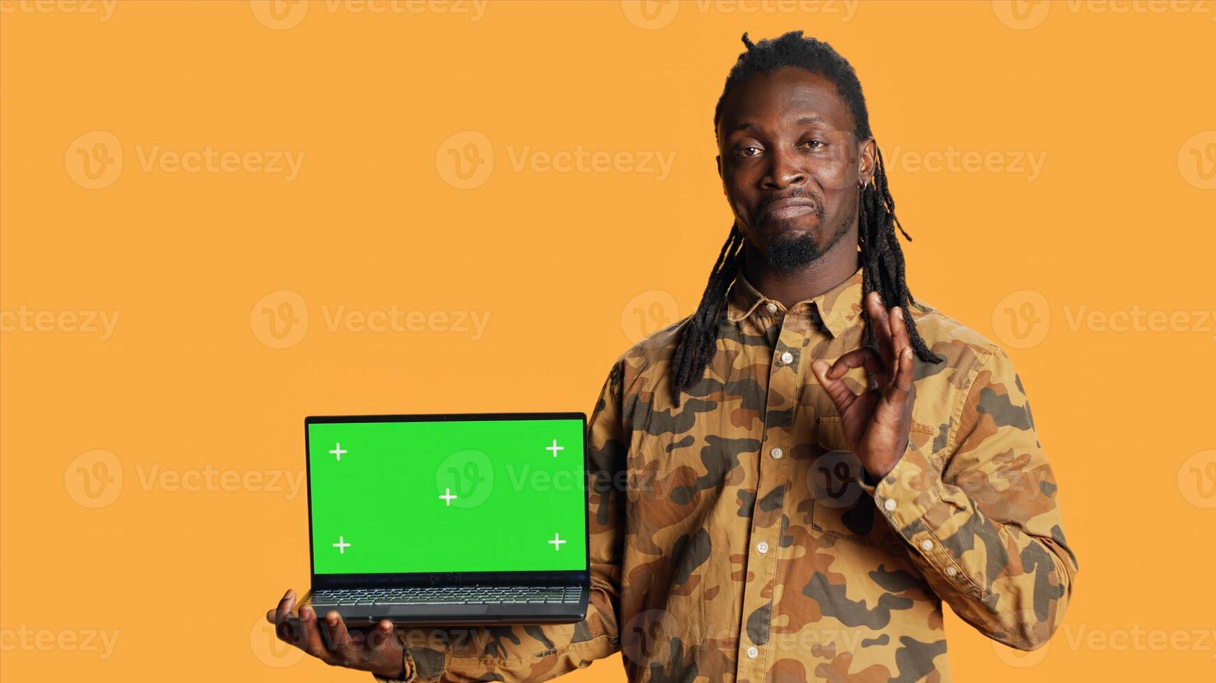 Person having laptop with greenscreen display on camera, posing with blank chromakey layout on wireless pc. Young man presenting computer with isolated copyspace screen in studio. photo