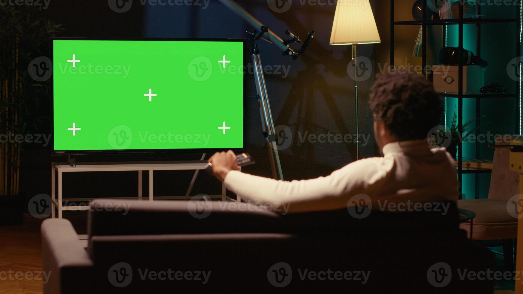 Man using isolated screen smart TV to watch news program broadcasting in living room. Cord cutter watching chroma key ultrawide television display showing VOD channel, relaxing on couch photo